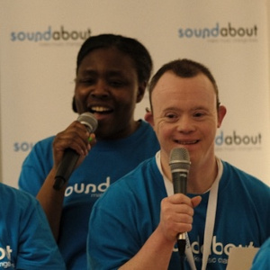 A picture of two people singing into microphones and smiling.